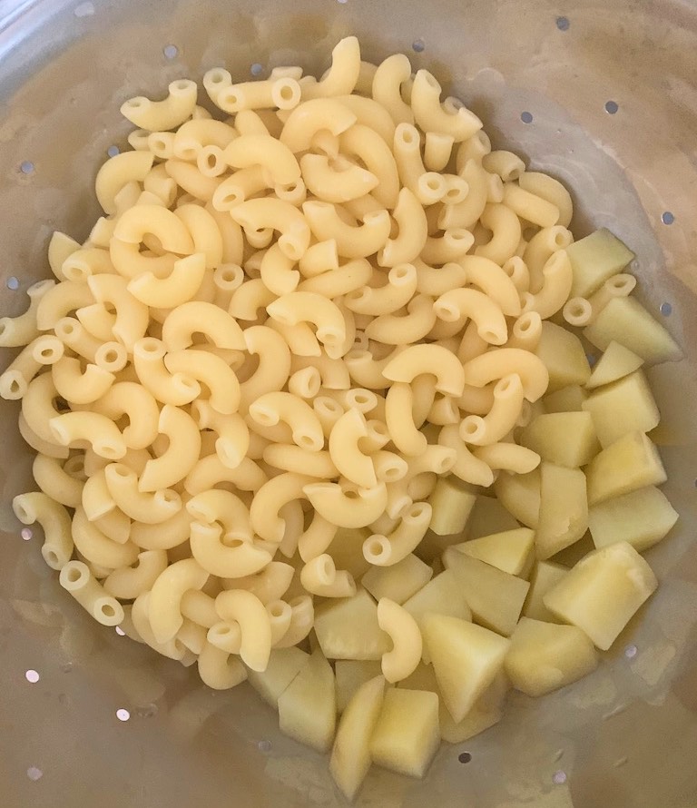 Cook the macaroni pasta and cubed potato pieces.